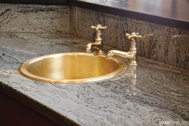 Brass sink contrasts with marble countertop