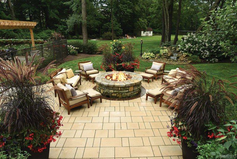 Cushioned chairs surround a gas fire pit