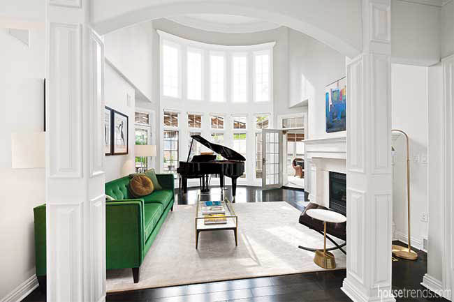 Wall of windows shines on a green sofa