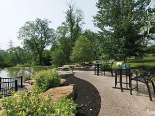 Seating areas overlook a pond in a spacious back yard
