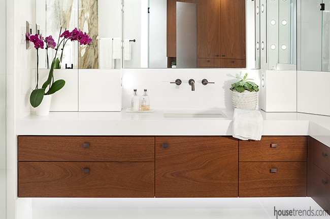 Thick white quartz counters top the mahogany floating vanities in this bathroom remodel.