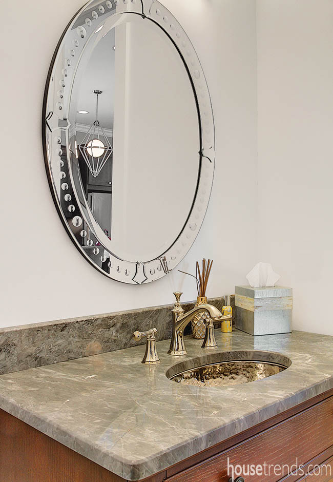 Oval mirror and hammered sink add texture to a powder room