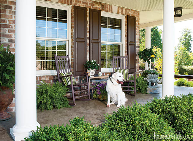 Rocking chairs sit under a covered front porch