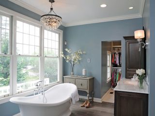A freestanding cast bathtub sits beneath a leaded-glass chandelier.