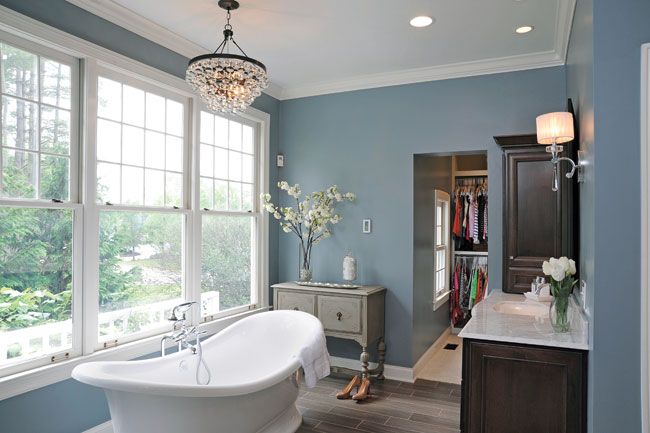 A freestanding cast bathtub sits beneath a leaded-glass chandelier.
