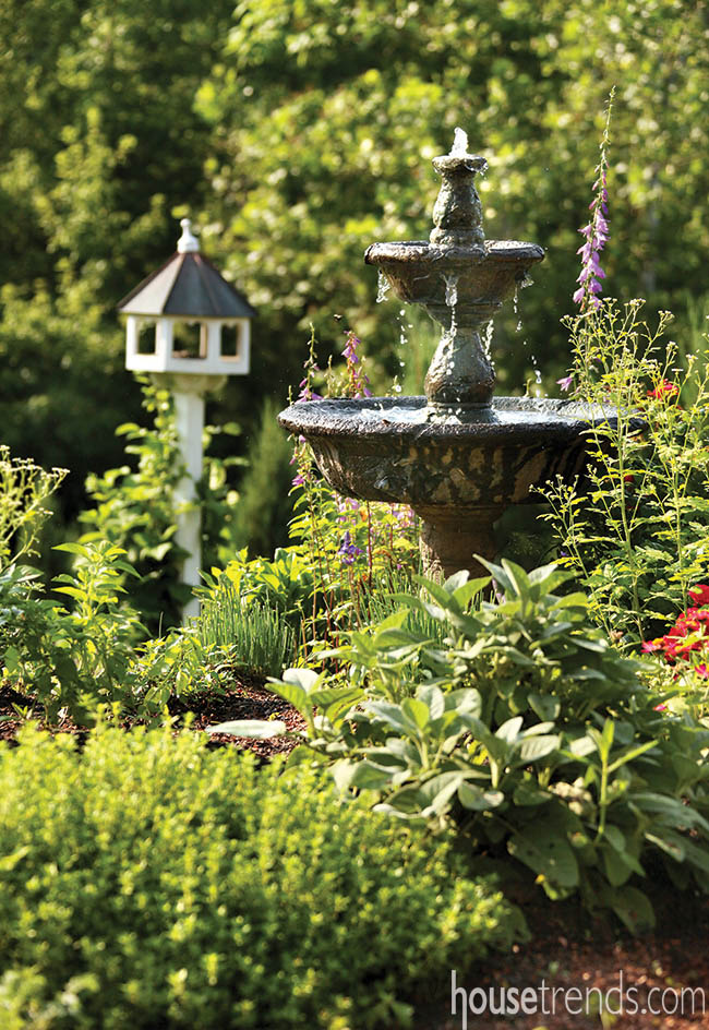Outdoor water fountain stands tall in an herb garden